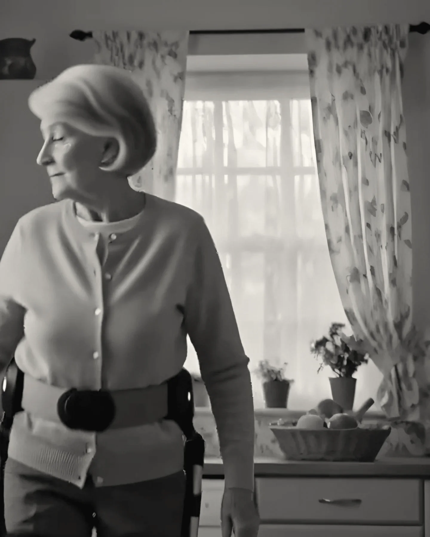 The woman standing in her own kitchen by the window